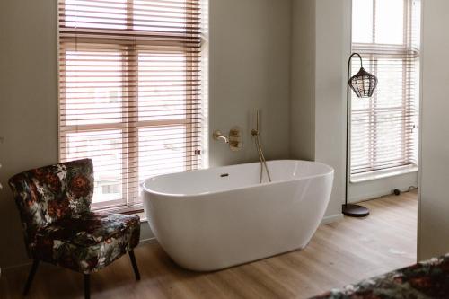 a large white tub in a bathroom with a chair at Hotel Restaurant Belv&eacute;d&egrave;re in Schoonhoven