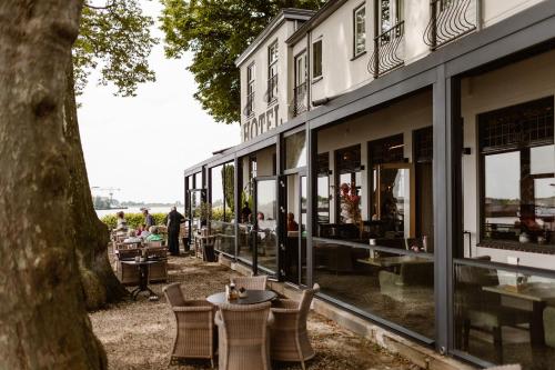 a building with tables and chairs next to a tree at Hotel Restaurant Belvédère in Schoonhoven