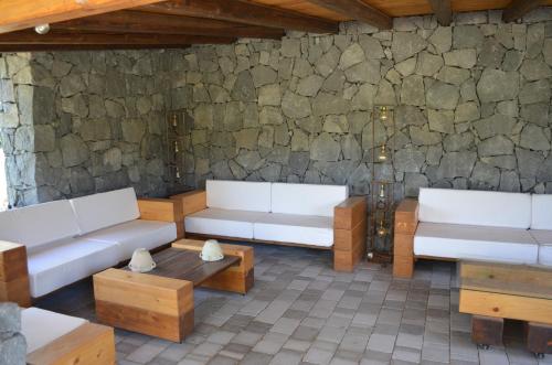a room with two white couches and a stone wall at Villa VEDA in Randazzo