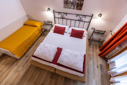 a bedroom with two beds with red pillows at Hotel Rabay in Brenzone sul Garda