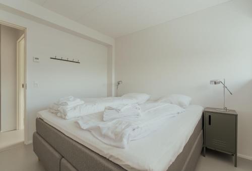 a white bedroom with a bed with white sheets at Nyrenoveret, moderne,hyggeligt hus in Leirvík