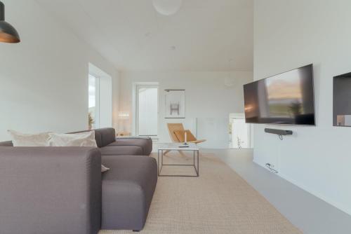 a living room with a couch and a tv at Nyrenoveret, moderne,hyggeligt hus in Leirvík