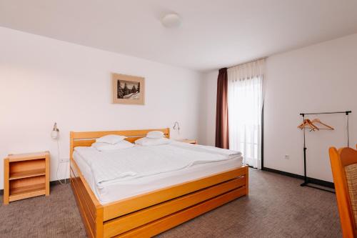 a bedroom with a large bed with white sheets at Lobogo Resort in Vlăhiţa