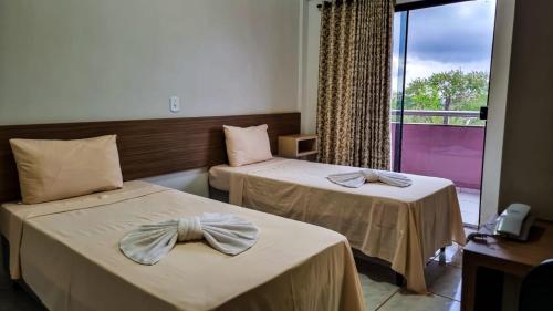 a hotel room with two beds with bows on them at Conforto Plaza Hotel in Capitão Leônidas Marques