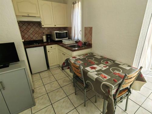 Il comprend une petite cuisine avec une table, des chaises et un four micro-ondes. dans l'établissement Charmant T2 en Pinède avec parking, véranda et terrasse, à 900m de la plage, idéal pour 4 personnes - FR-1-607-41, au Cap d'Agde
