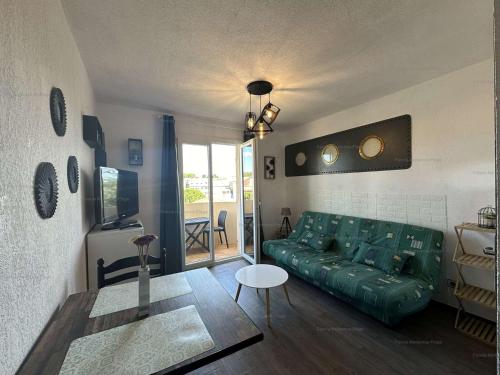 un salon avec un canapé vert et une table dans l'établissement Studio avec balcon, piscine, parking privé - Narbonne Plage - FR-1-229B-102, à Narbonne