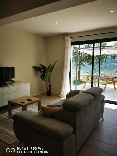 a living room with a couch and a large window at Gîte les Monteils in Vesseaux