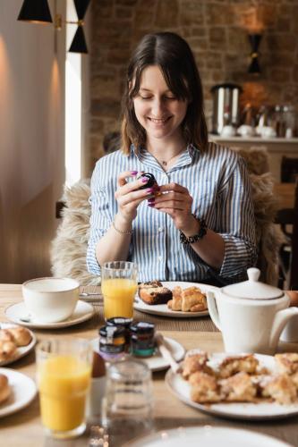 uma mulher sentada à mesa a tirar uma fotografia à comida em Revi Mountain Resort Boutique Hotel em Kalavrita