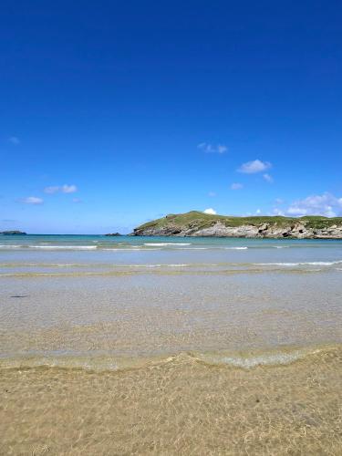 a sandy beach with the ocean in the background at Nook Cottage Seaside Charm & Countryside Calm in Newquay