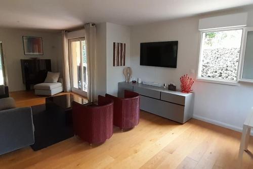 - un salon avec des chaises rouges et une télévision dans l'établissement Deauville, Appartement 115 m2 - 3 chambres, en Rez de jardin, à Deauville