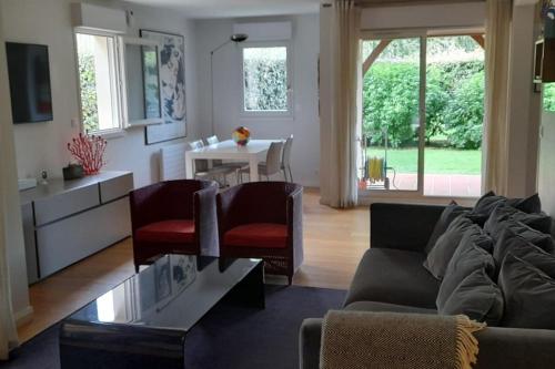un salon avec un canapé, des chaises et une table dans l'établissement Deauville, Appartement 115 m2 - 3 chambres, en Rez de jardin, à Deauville