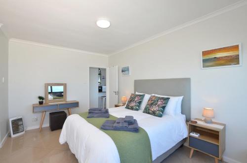 a bedroom with a large white bed and a mirror at Seaforever Apartment in Yzerfontein