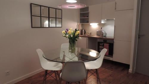 une table en verre avec des chaises et un vase de fleurs. dans l'établissement Le Sage, à Toulouse