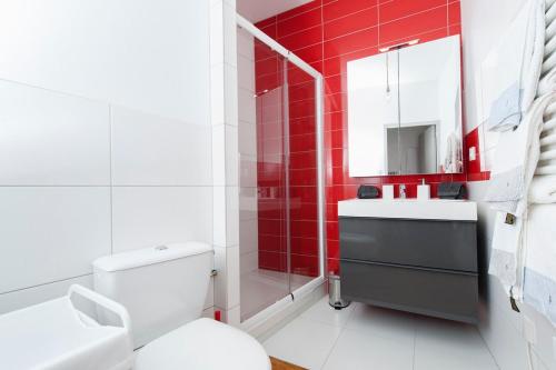 La salle de bains est pourvue de toilettes blanches et d'un mur rouge. dans l'établissement Le Sage, à Toulouse