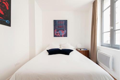 - un lit blanc avec 2 oreillers dans la chambre dans l'établissement Le Sage, à Toulouse