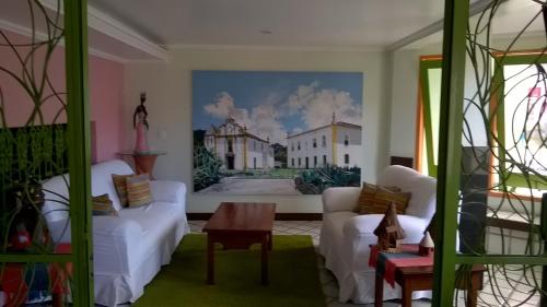 a living room with white furniture and a painting on the wall at Hotel Terra Mater in Porto Seguro