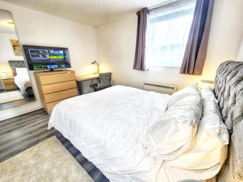 a bedroom with a bed and a flat screen tv at Brand New Flat - Canary Wharf in London