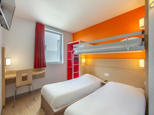 a room with two beds and a desk and a bunk bed at Premi&egrave;re Classe Chartres Sud - Barjouville in Chartres