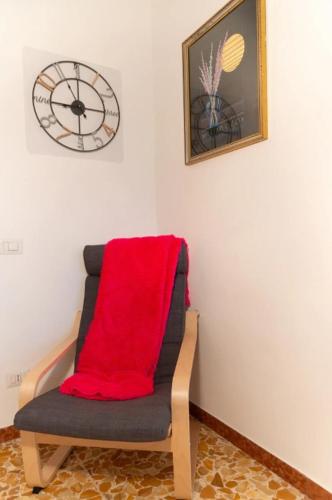 a chair with a red blanket sitting in a room with a clock at Villa Anna - Bike Friendly in Buonconvento