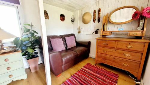 a living room with a brown leather couch and a dresser at Treguth Glamping Unique Experience - Themed Huts in Saint Day
