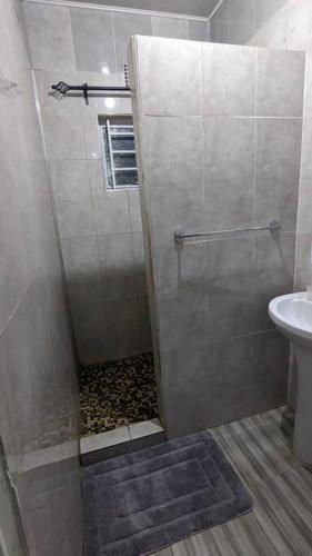 a bathroom with a shower with a toilet and a sink at Kumalo apartment in Lusaka