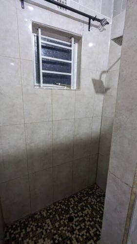 a bathroom with a window and a tiled shower at Kumalo apartment in Lusaka