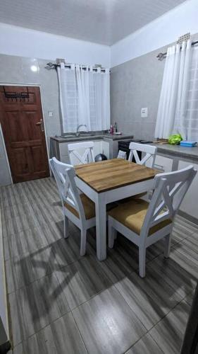a kitchen with a wooden table and white chairs at Kumalo apartment in Lusaka