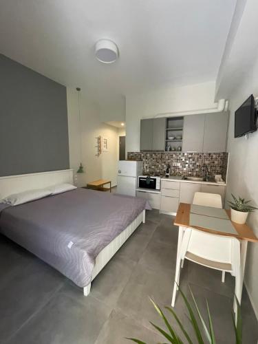 a bedroom with a bed and a table and a kitchen at Buganvillas Studios in Preveza