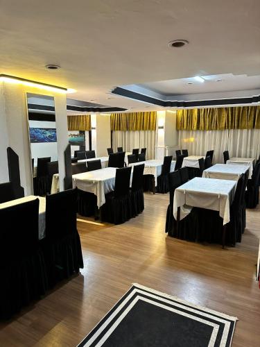 a restaurant with white tables and black chairs at NIGRUM HOTEL in Nevsehir