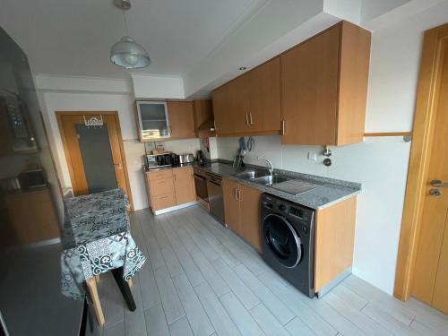 a kitchen with a washing machine and a sink at GARDEN & BEACH HOUSE in Figueira da Foz