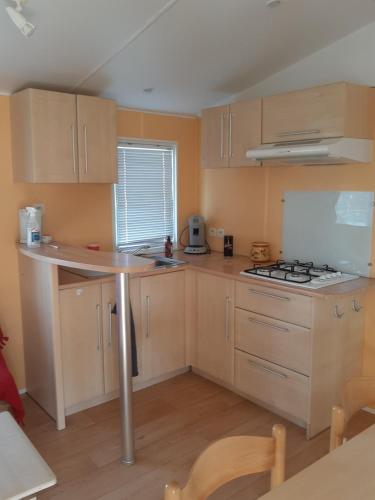 une cuisine avec des armoires en bois et un four à plaques de cuisson dans l'établissement Mobil home, à Saint-Hilaire-en-Lignières