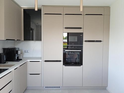 a white kitchen with white cabinets and appliances at Apartament Monika Dziwnówek Wrzosowo z jacuzzi in Wrzosowo
