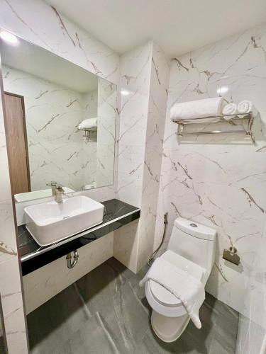 a white bathroom with a sink and a toilet at เวลโกรว์ โฮเทล - Wellgrow Hotel in Ban Bang Kha