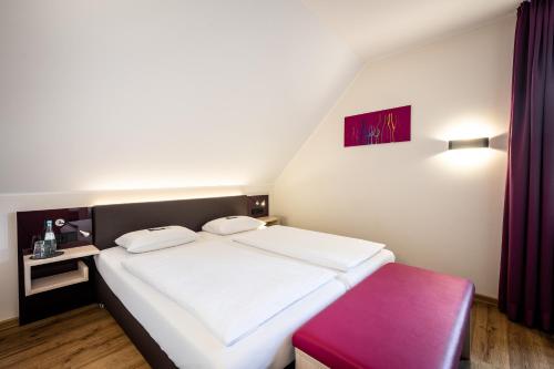 a bedroom with a white bed and a red stool at Weinhotel Restaurant Klostermühle in Ockfen