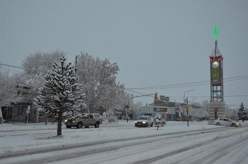 a snow covered street with a clock tower and cars at Rosetta in Malargüe