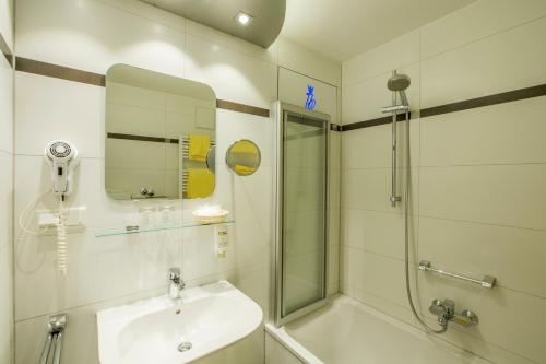 a white bathroom with a sink and a shower at Hotel Brunner in Amberg