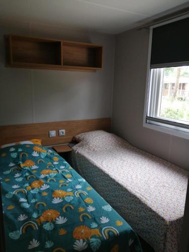 une petite chambre avec deux lits et une fenêtre dans l'établissement Mobil Home bord d'eau Camping 4 étoiles Les Viviers, à Lège-Cap-Ferret
