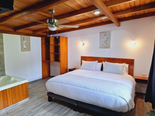 a bedroom with a white bed and a wooden ceiling at Royal River Suites & Spa Aparthotel in Mindo