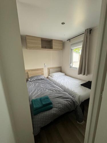 a small bedroom with two beds and a window at Mobil-Home in Lège-Cap-Ferret