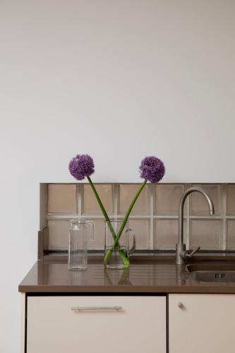 a glass vase with purple flowers sitting on a kitchen counter at Bob W London Tower Hill - Residences in London