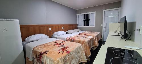 a hotel room with two beds and a television at Locapart Hospedagens in Chapecó