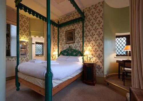 a bedroom with a four poster bed and floral wallpaper at The Hunting Tower in Baslow