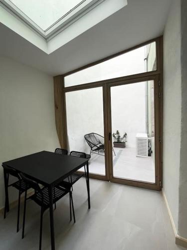 - une table et des chaises noires dans une chambre avec fenêtre dans l'établissement Magnifique T2 cœur de ville, à Sète