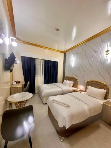 a hotel room with two beds and a table and a chair at Galaxy Star Hotel in Dubai
