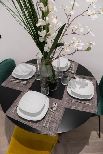 a black table with white plates and a vase of flowers at barneys design apartment in Taranto
