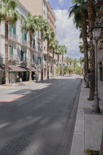 an empty street with palm trees and buildings at barneys design apartment in Taranto