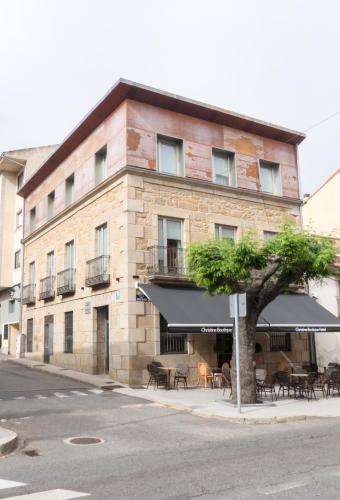 a building with tables and umbrellas in front of it at Christine Boutique Hotel in El Barraco