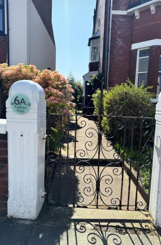 a gate to a house with bushes and flowers at The Eaves - Victorian second floor, open plan apartment in Southport