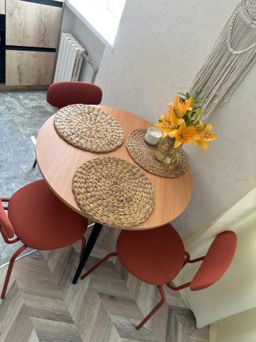 una mesa de madera con sillas y un jarrón de flores. en Terracotta en Kremenchuk