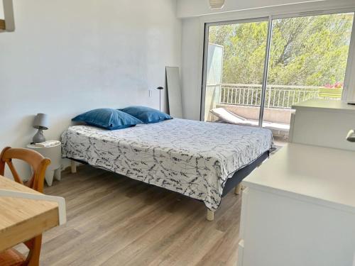 une chambre avec un lit avec des oreillers bleus et une fenêtre dans l'établissement Appartement 72m² à Saint-Raphaël (83), à Saint-Raphaël